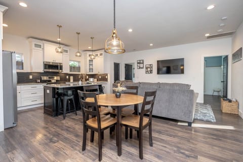 Welcome to the bright and spacious open-concept heart of the home! This view shows the dining area, cozy living room with a large couch, and the modern kitchen island.