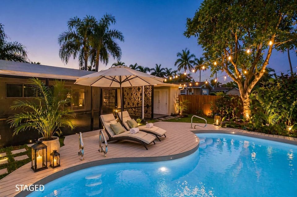 Private tropical backyard oasis featuring a sparkling pool, lounge chairs, ambient string lighting, and lush landscaping—perfect for relaxing, swimming, or enjoying warm Florida evenings.