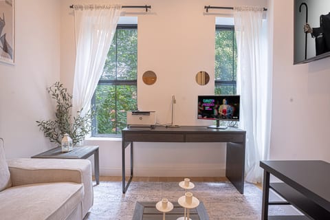 Cozy room with sofa, desk, printer, and natural light—perfect for work or relaxing