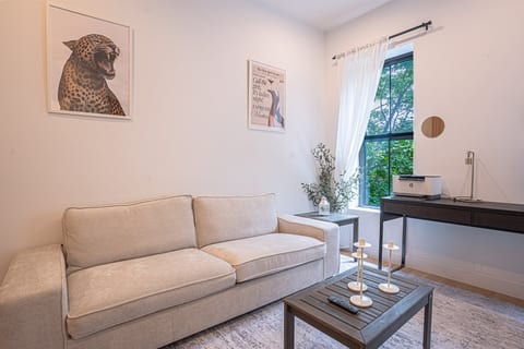 Cozy room with sofa, desk, printer, and chic wall art—ideal for work and relaxation