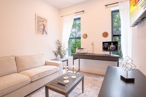 Bright, cozy living room with sofa, desk, TV, and elegant décor.