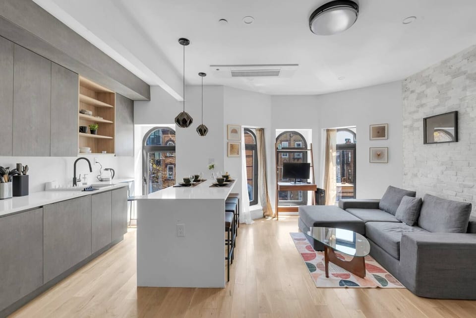Bright, modern open-concept living and kitchen with a sleek island and arched windows — your stylish Brooklyn retreat.