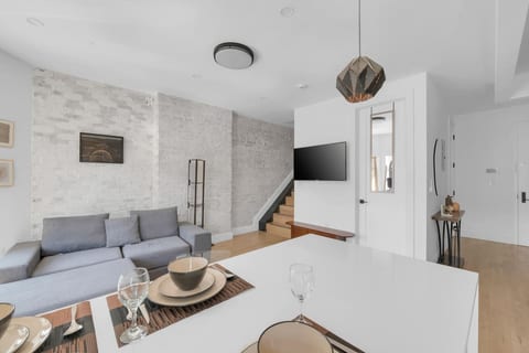 Comfortable living and dining space with a plush sofa, smart TV and stone accent wall — relax and unwind.