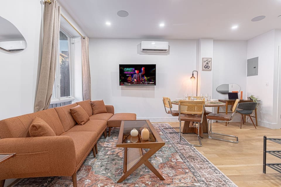 Spacious open-plan living + dining with a cozy sectional, smart TV, and A/C for year-round comfort. Natural light, warm textures, and a table set for four make it perfect for movie nights, meals in, and laid-back hangs