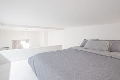 Cozy loft bedroom with a comfortable full-size bed, soft bedding, and a bright, airy atmosphere. Overlooking the main living area, this elevated sleeping space offers privacy while maintaining an open, modern feel