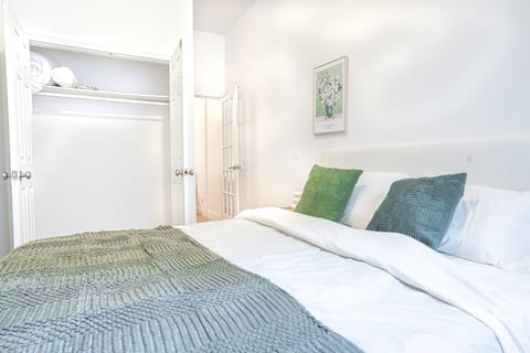 Cozy bedroom with layered bedding and a roomy closet — unpack and settle in for a relaxed Manhattan getaway.