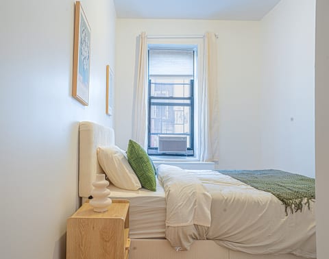 Serene bedroom with a plush bed, fresh linens, and bright natural light — a restful retreat in this Upper East Side home.