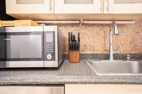 Well-equipped kitchen counter with microwave, cookware, and a tiled backsplash — prep your meals with ease.
