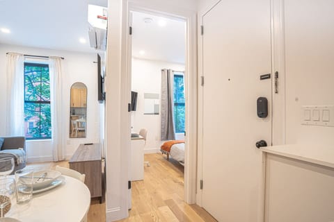 Bright entryway featuring smart lock, leading to open living and bedroom areas for secure welcome.