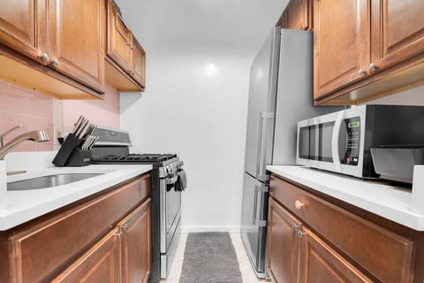 Fully equipped kitchen with gas stove, full-size fridge, and ample cabinets — cook in or grab dinner on nearby 5th & 7th Avenue.