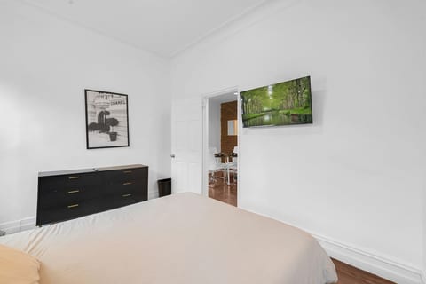 Restful bedroom with a comfortable bed, dresser, and wall-mounted smart TV — quiet nights in one of Brooklyn's most beloved neighborhoods.