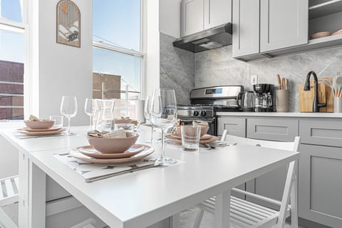Eat-in kitchen set for the group — full-size stove, prep space, and dishware ready for home-cooked meals near LaGuardia.