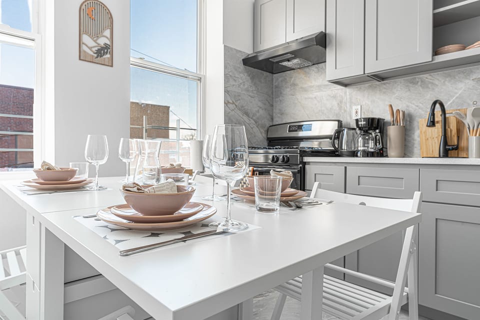 Eat-in kitchen set for the group — full-size stove, prep space, and dishware ready for home-cooked meals near LaGuardia.