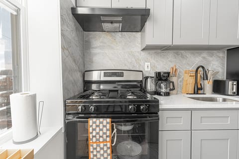 Modern kitchen with full-size stove, coffee maker, and ample white cabinets — everything you need to cook in comfortably.