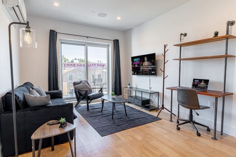 Living room with smart TV, armchair and sofa in bright Scandinavian Bushwick balcony loft