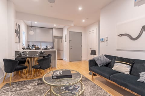 Open-plan dining and living room with modern furnishings, wood flooring, and natural light