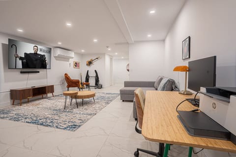 Expansive basement with TV, ample seating, dedicated workspace and music corner for creativity