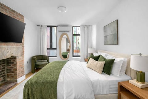 Spacious bedroom with brick fireplace, TV, and modern design