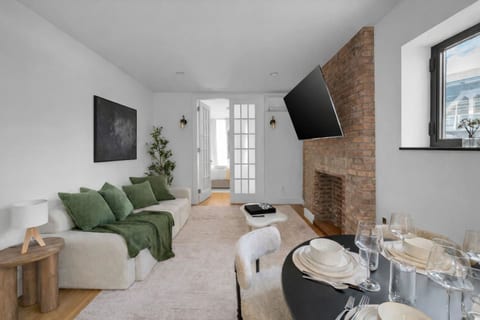 Open living space with brick fireplace, TV, and dining area.