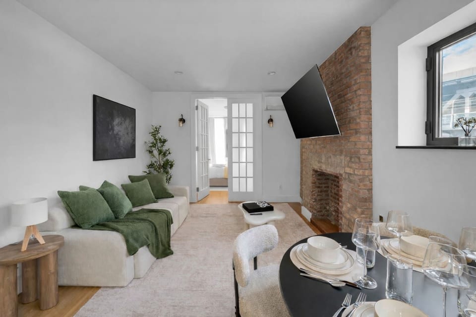 Open living space with brick fireplace, TV, and dining area.