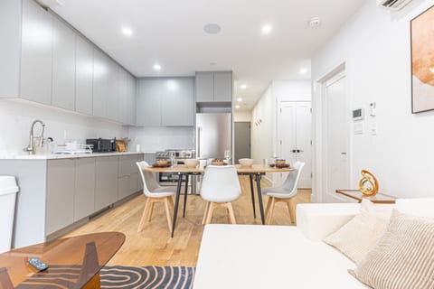 Modern kitchen with cabinets, stainless appliances, and a dining table with white chairs.