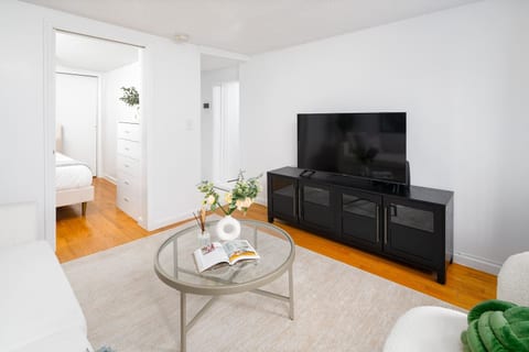 Spacious living room with smart TV, coffee table & warm hardwood floors