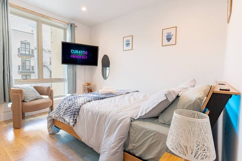 Bedroom with queen bed, smart TV and warm lighting in calm Scandinavian Bushwick retreat