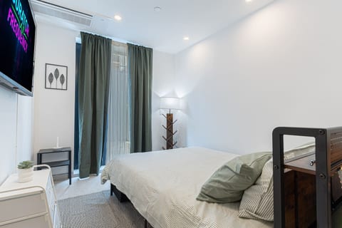 Restful bedroom with a plush queen bed, fresh linens, and a smart TV — a quiet retreat after exploring Brooklyn.