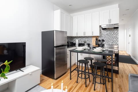 Modern kitchen with island dining, mosaic backsplash, and adjacent TV lounge