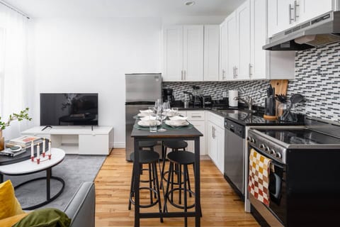 Open kitchen/living space with island dining, cozy sofa, and natural light