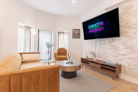 Inviting living room with plush seating, a statement stone wall and large smart TV — unwind after exploring the city.