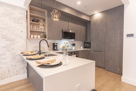 Modern full kitchen with a quartz island, sleek cabinetry and stainless appliances — cook in with ease in Bushwick.