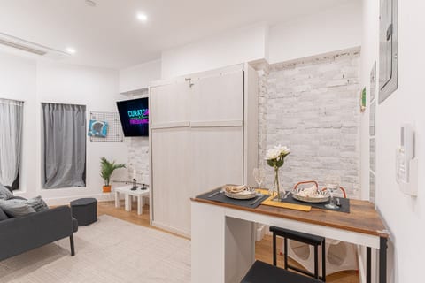 Sleek kitchen-and-dining nook with a wood counter set for two and full appliances — cook, eat and relax in this smart studio layout.