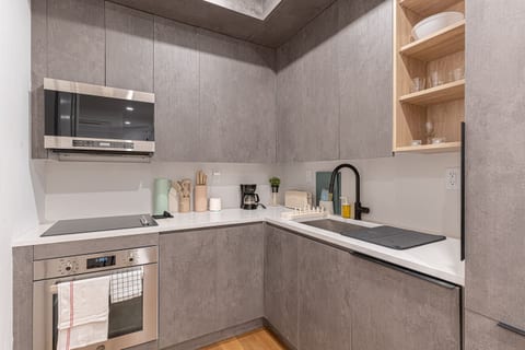 Fully equipped kitchen with stainless microwave, cooktop, sleek cabinetry and quartz counters — cook in and save while you explore Brooklyn.