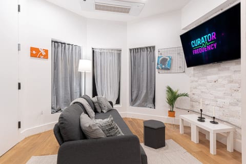 Inviting living area with a plush sofa, soft pillows and greenery — unwind here after a day exploring NYC, then hop the nearby subway.