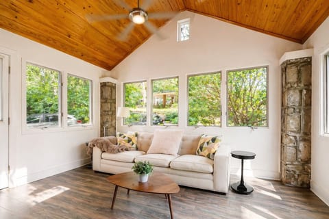 Sunlit lounge with vaulted wood ceiling, big windows, and garden views