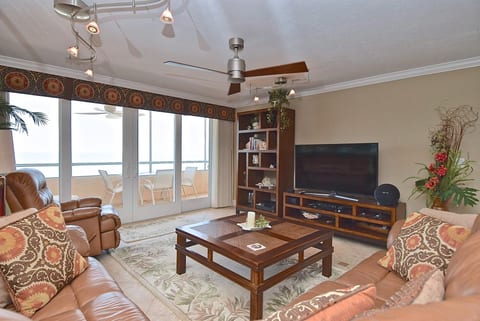 Spacious living room with comfortable leather seating, a large smart TV, and direct access to the screened/glassed lanai.