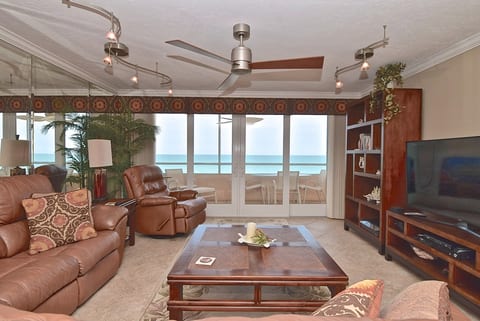 Relax in the spacious living room while enjoying breathtaking Gulf views through floor-to-ceiling sliding glass doors leading out to the screened/glassed lanai