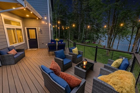 Lakeside evening deck with cozy seating, dining space, and string lights
