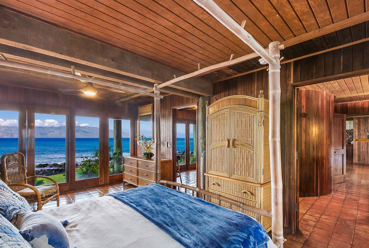 The downstairs master bedroom sits oceanside with a direct view of the vast Pacific and the gentle silhouette of Molokai island from this en suite bedroom.