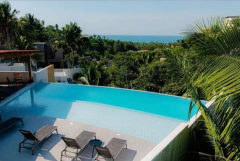 Guests enjoy access to exceptional resort-style amenities, including a stunning rooftop with panoramic ocean views, a sparkling pool, barbecue area, expansive green space for yoga or relaxing, and comfortable seating for dining, socializing, or remote work.