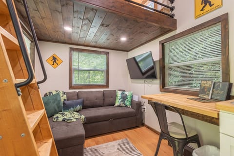 The cozy living area features a Smart TV, comfortable seating, and peaceful wooded views.