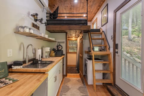 Smart tiny home design with loft access, a kitchenette, and an all-in-one washer/dryer combo.