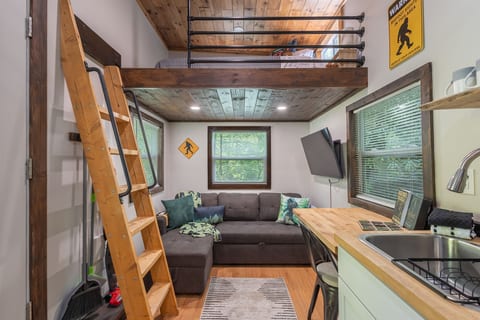 A cozy open-concept living area with loft access, comfortable seating, and Bigfoot-themed touches throughout.