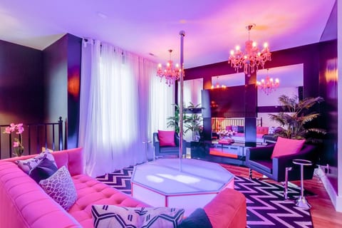 Entertainment room with custom neon mood lighting, dance pole, and plush group seating.
