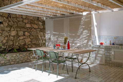 Charming outdoor dining area with traditional Capri vibes. Shaded by a rustic pergola, this bright space is perfect for long, relaxing meals surrounded by stone walls, soft sunlight, and island tranquility.