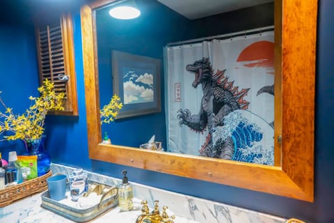 Unique, art-filled bathroom with bold décor and fun personality, complete with the famous Godzilla shower curtain that guests love. A playful touch that captures the home’s quirky charm.