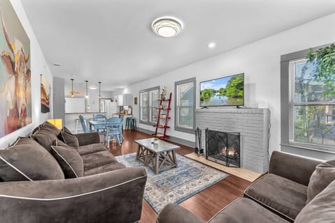 Bright open living room blending farmhouse charm and modern comfort, with cozy seating, restored fireplace, and Smart TV. A perfect space to relax after exploring downtown San Antonio.