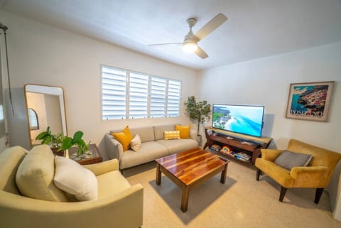 A bright and cozy living room with comfy seating, warm décor, and a large TV, perfect for unwinding after a day in San Juan.