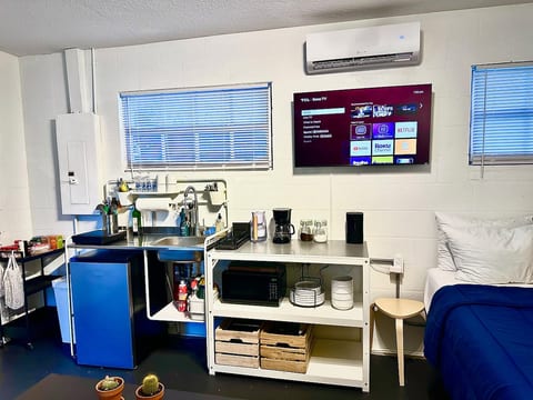 Coffee bar stocked with fresh grounds, sugar, and mugs to kickstart your day. Mini kitchen with fridge, microwave, and dishes—ready when you are.
